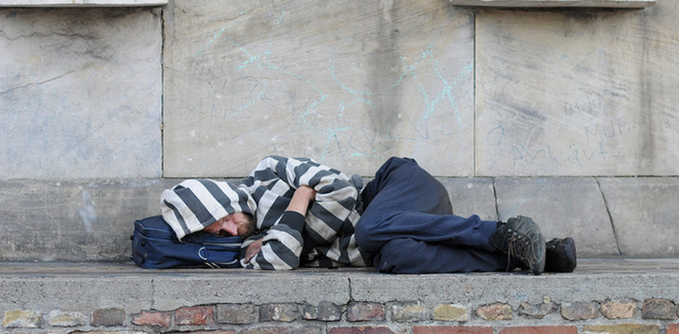 A homeless man sleeping on a wall