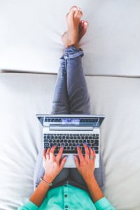 Woman sits at laptop on her sofa.